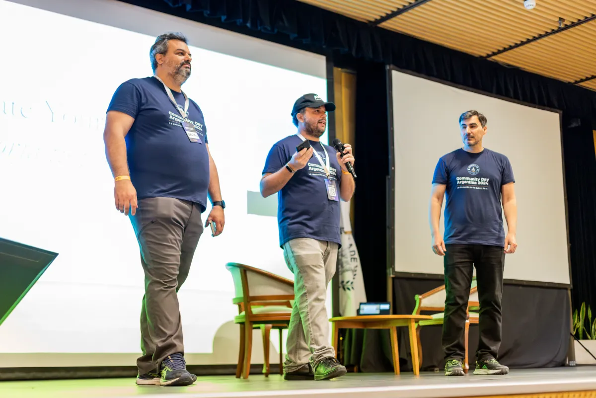 Tres organizadores en el escenario principal con camisetas del evento