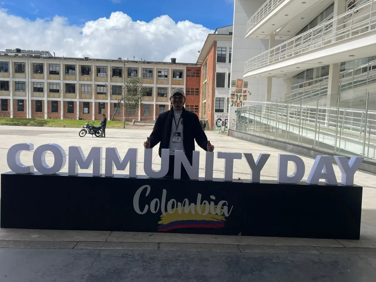 Asistente junto a la senalizacion del AWS Community Day Colombia 2025